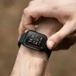 Close-up de um relógio esportivo preto no pulso de uma pessoa, exibindo dados de frequência cardíaca, tempo de exercício e outras métricas de atividade física.
