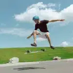 Jovem praticando manobras radicais com longboard em um dia ensolarado, simbolizando superação e autoconfiança.