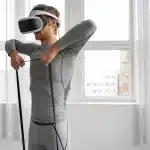 Homem utilizando óculos de realidade virtual enquanto realiza exercícios com faixa de resistência, simbolizando tecnologia e saúde.