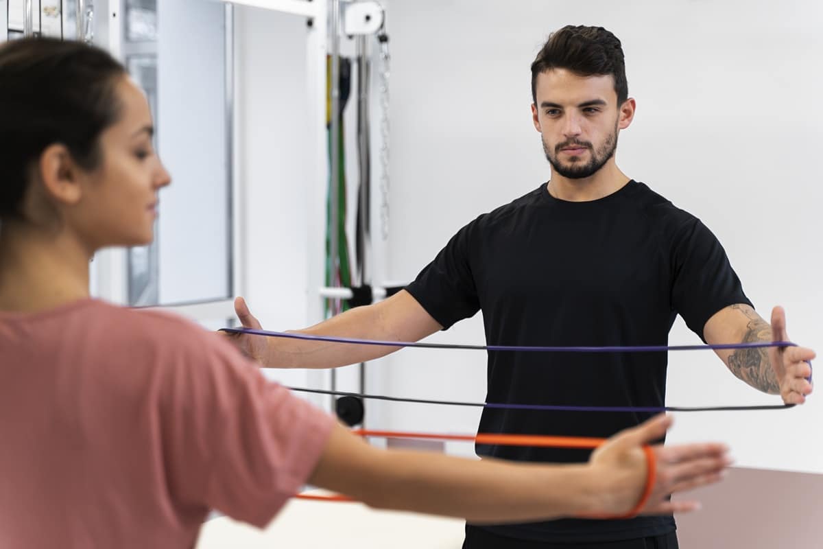 Pessoa fazendo exercício de propriocepção com elásticos na fisioterapia, acompanhada por um profissional.
