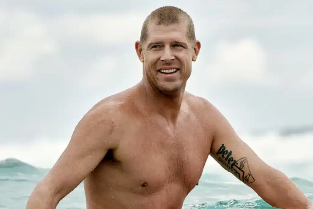 surfista dentro do mar olhando para o lado com expressão sorridente após sair de uma onda