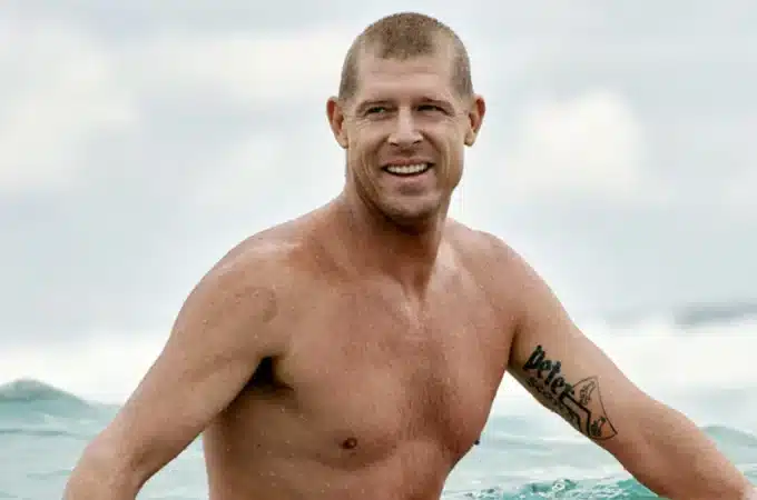 surfista dentro do mar olhando para o lado com expressão sorridente após sair de uma onda