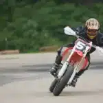 piloto de supermoto inclinado em uma curva na pista de asfalto durante corrida