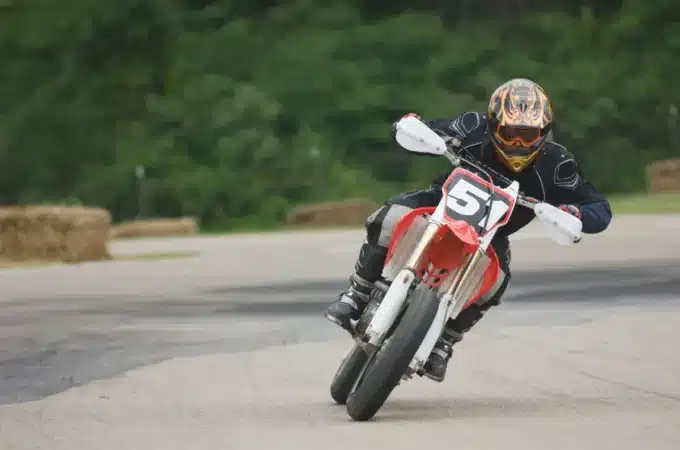 piloto de supermoto inclinado em uma curva na pista de asfalto durante corrida